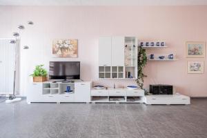 a living room with white furniture and a flat screen tv at Ferienhaus Hunsrückliebe in Liederbach