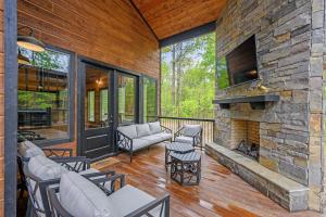 a living room with a fireplace and a stone wall at Fun & Inviting Modern Luxury 4br Retreat At Broken Bow Lake Features Hot Tub, Fire Pit, Playground And More Once In A Blue Moon By Boutiq in Broken Bow