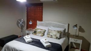 1 dormitorio con 1 cama con toallas en Cottage K'Gari, en Franschhoek