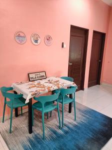 a table and chairs in a room with pink walls at NazLa Homestay Pendang in Pendang