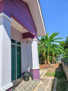 fioletowo-biały dom z koszem na śmieci na zewnątrz w obiekcie NazLa Homestay Pendang w mieście Pendang