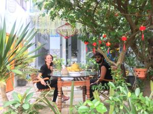 een man en vrouw aan een tafel in een tuin bij Cherry Garden Homestay in Hội An