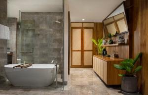 a bathroom with a tub and a shower and a sink at Adiwana Suweta in Ubud