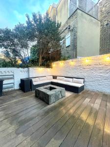 un patio con sofá en una terraza de madera en NEW! Luxury 1 bed garden apartment Camden Town, en Londres