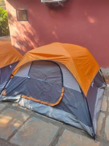 une tente orange et grise installée à côté d'un bâtiment dans l'établissement Cosmos @ Greenspace, à Siolim