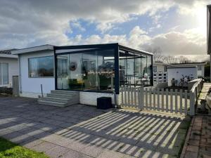 een huis met glazen deuren op een patio bij Luxe chalet direct aan het water met strand in Lith