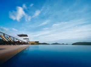 uma piscina com cadeiras e guarda-sóis junto à água em PARKROYAL Langkawi Resort em Pantai Cenang