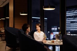 a man and woman sitting at a table in a restaurant at Sheraton Grand Hiroshima Hotel in Hiroshima