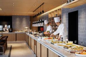 three chefs preparing food in a restaurant kitchen at Sheraton Grand Hiroshima Hotel in Hiroshima