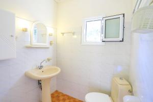 een badkamer met een wastafel, een toilet en een raam bij Antigoni Villas in Longós