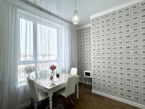 een witte eetkamer met een tafel en een raam bij Квартира ЖК Apple city in Astana