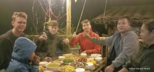 a group of people sitting around a table with food at Quang Thuận Bản Giốc Homestay in Cao Bằng