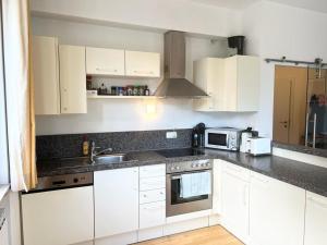 a kitchen with white cabinets and a sink and a microwave at Four Seasons Getaway - 3 minutes From Town Centre in Zell am See