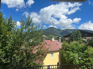 una casa amarilla con árboles y montañas en el fondo en Four Seasons Getaway - 3 minutes From Town Centre, en Zell am See