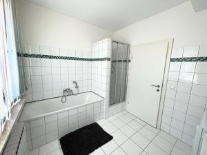een wit betegelde badkamer met een bad en een douche bij Four Seasons Getaway - 3 minutes From Town Centre in Zell am See