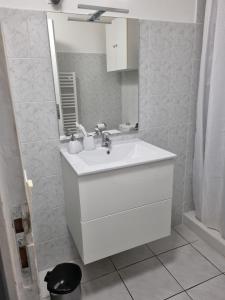 a white bathroom with a sink and a mirror at Location saisonnière in Agde