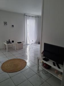a living room with a television and a tiled floor at Location saisonnière in Agde