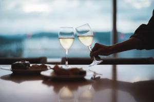 a person holding two glasses of white wine on a table at Sheraton Grand Hiroshima Hotel in Hiroshima