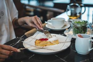 a person eating a piece of cake on a plate at Sheraton Grand Hiroshima Hotel in Hiroshima