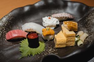 a plate of sushi on a black plate at Sheraton Grand Hiroshima Hotel in Hiroshima