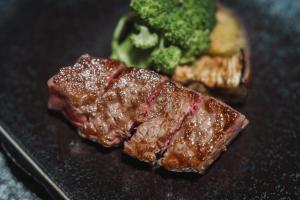 a piece of steak and broccoli on a black plate at Sheraton Grand Hiroshima Hotel in Hiroshima