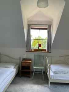 a bedroom with two beds and a chair and a window at Zaciszne Apartamenty in Poddąbie