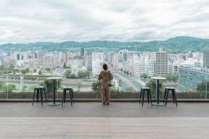 a woman standing on top of a building looking at a city at Sheraton Grand Hiroshima Hotel in Hiroshima