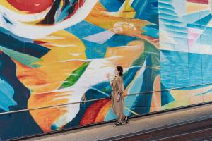 a woman walking in front of a mural at Sheraton Grand Hiroshima Hotel in Hiroshima