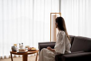 a woman sitting on a couch in a living room at Sheraton Grand Hiroshima Hotel in Hiroshima