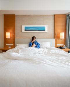 a woman sitting on top of a bed at Sheraton Grand Hiroshima Hotel in Hiroshima