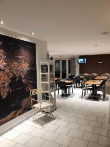 a waiting room with tables and chairs and a large painting at Rev'hotel in Ribérac