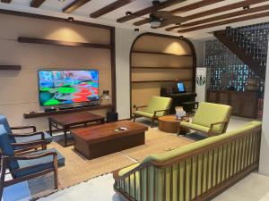 a living room with a flat screen tv and chairs at TROPICAL HOUSE RIVERSIDE RETREAT in Thuan An