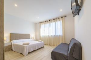 ein Schlafzimmer mit einem weißen Bett und einem Sofa in der Unterkunft HomeHolidaysRentals Music - Costa Barcelona in Pineda de Mar