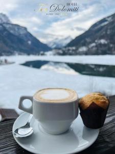 una taza de café y un muffin en una mesa en Hotel TEA Dolomiti en Alleghe