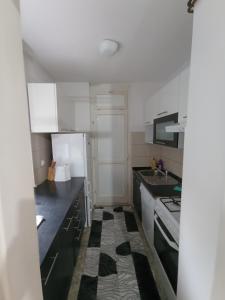 eine Küche mit weißen Schränken und schwarzen Arbeitsplatten in der Unterkunft Apartman Dina in Bihać