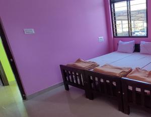 ein lila Zimmer mit einem Bett und einem Fenster in der Unterkunft STAYMAKER Madhu Residency in Sāgar