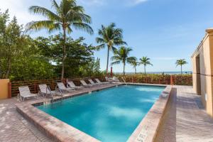einen Pool mit Stühlen und Palmen in der Unterkunft Estero Island Beach Villas 706, 2 BR, Penthouse, Gulf Front, Pool, Sleeps 6 in Fort Myers Beach
