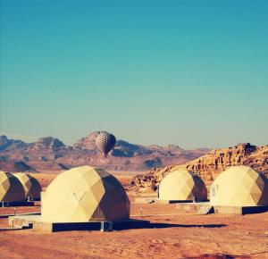 Amanda Luxury Camp في وادي رم: مجموعة من الخيام في الصحراء مع الجبال