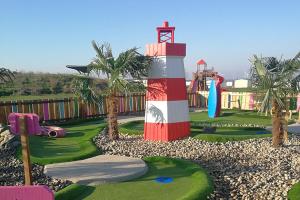 un campo de golf con un faro y un parque infantil en MOONSTONE en Leysdown-on-Sea