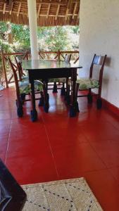 a dining table and chairs in a room at Les Datchi Cottages in Diani Beach