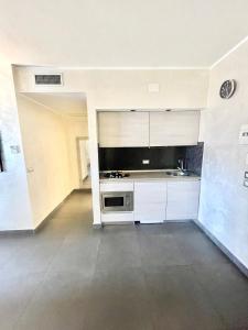 コゼンツァにあるSuite Roomsの白いキャビネットとシンク付きの広いキッチン