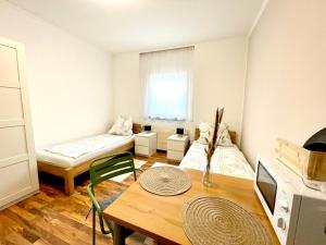 a living room with a table and a room with two beds at SmartRooms24 in Villach