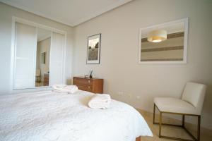 biała sypialnia z łóżkiem i krzesłem w obiekcie Los Robles de Los Arqueros golf 3 bedrooms apartment. w mieście Benahavís +14 zdjęć