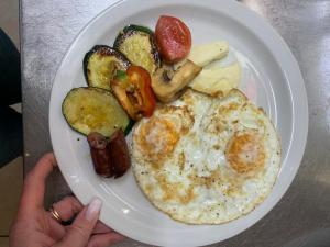 a person holding a plate of food with eggs and vegetables at La Veranda Hotel in Larnaca