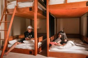 mężczyzna i kobieta siedzący na łóżkach piętrowych w obiekcie Escape Bajo w Labuan Bajo