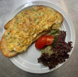 a white plate with an omelet and a sandwich and salad at La Veranda Hotel in Larnaca