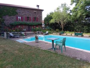 a pool with a table and chairs next to a building at gîte de Vialette in Rachat