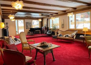 uma sala de estar com cadeiras, uma mesa e um piano em B&B Villa Stelvio em Sta Maria Val Müstair