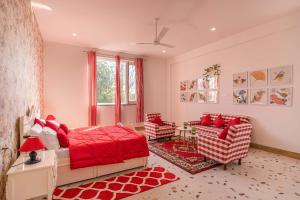 een slaapkamer met een rood bed en 2 stoelen bij StayVista at Colour Bloom - Pet Friendly Home with Swimming Pool 
