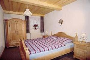 マウトにあるFerienwohnung Christaのベッドルーム1室(大型ベッド1台、木製ドレッサー付)
